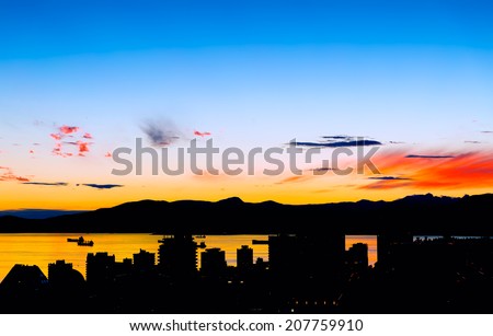 Vancouver and bay at sunset with silhouetted buildings against vivid colors. Aerial view. Copy space.