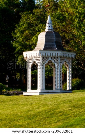 White gazebo in a lush green setting of lawn and trees. Location: Bar Harbor, Maine, USA