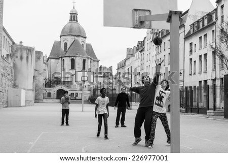 PARIS-DEC 30,2013:Unidentified boys play basketball in an open space between buildings in an historic neighborhood.Use of the basketball hoops is free to local Parisians to encourage healthy activity.