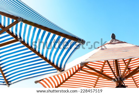 Colorful striped beach umbrellas against a cyan sky. View from underneath looking up. Copy space.