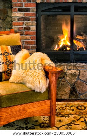 Chair by a cozy fireplace with a crackling fire. Style is rustic elegance, lodge, upscale cabin