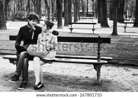 PARIS-JAN. 4, 2014: An unidentified couple sitting on a park bench at the Luxembourg Gardens, a popular romantic destination in Paris. Black and white image with grain added for a retro film effect.