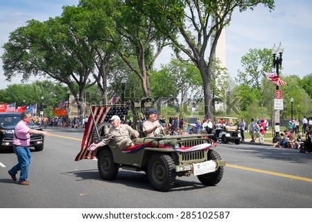 WASHINGTON DC-May 25,2015: At the Memorial Day Parade, a bystander runs up to shake hands with an elderly veteran of the decorated WWII 99th Infantry Division, riding in the parade in a vintage jeep.