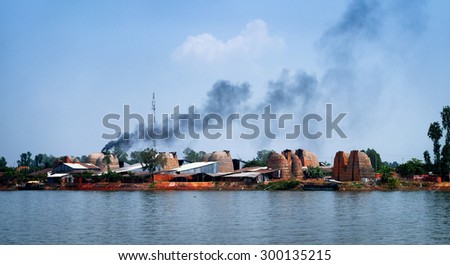 Vietnam brick and ceramic industry kilns shaped like beehives along the Mekong River produce plumes of black smoke. The kilns use a variety of fuels, including coal and rice husks.
