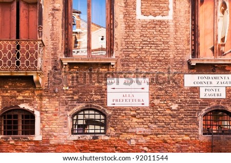 Venice, Italy -- ancient brick building wall with street signs, windows with reflections.  Closeup view of details.
