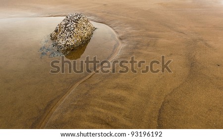 zen rock in pool of water with reflection, in a natural setting on a beach with gold sand, room for copy, horizontal