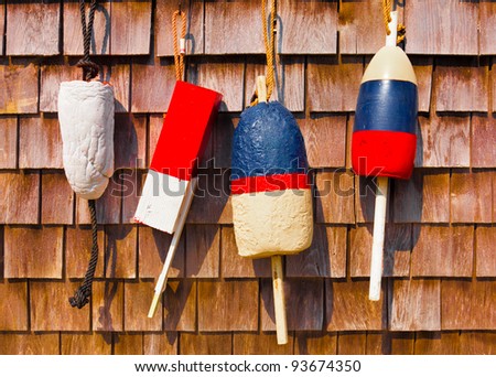 Red white and blue vintage fishing buoys hanging on wood shingled wall