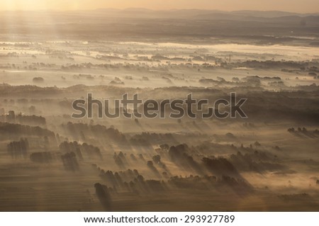 Morning fog illuminated soft rays of the morning sun in the suburbs Pszczyna photographed from the plane.