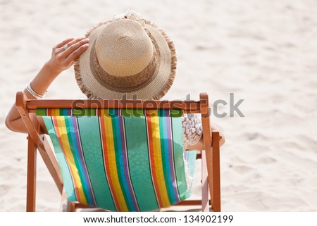 Woman sitting on beach chair looking at sea