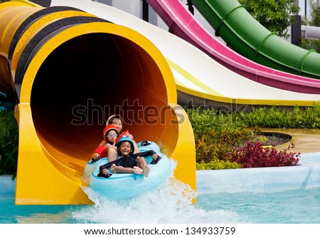 Boys and mother playing in water park in summer