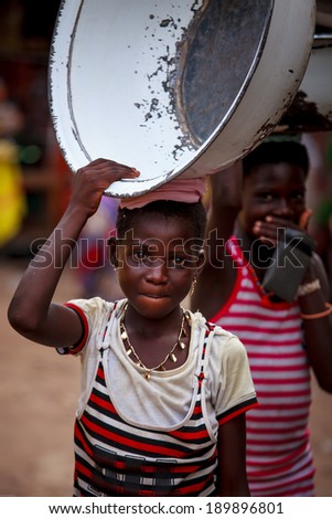 ACCRA, GHANA - MARCH 19: Unidentified young African girl carry big basin on her head on March 19, 2014 in Accra, Ghana. Carrying things on head is general skill of African girls and women.