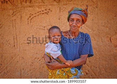 TAMALE, GHANA - MARCH 24: Unidentified old African woman holding baby on March 24, 2014 in Tamale, Ghana. African elders always take care for baby while young family's members go to work.