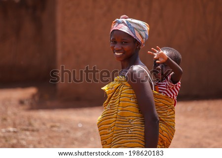 TAMALE, GHANA - MARCH 24: Unidentified African woman carrying her son on back on March 24, 2014 in Tamale, Ghana. Ghana is one of the most popular tourists destination in Africa.