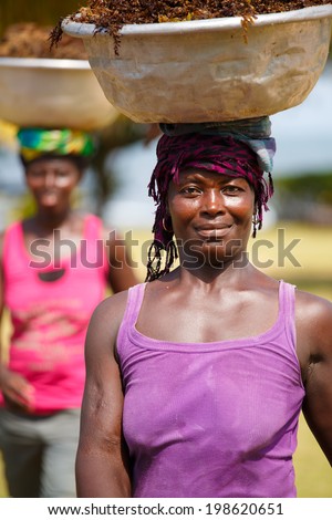 TAKORADI, GHANA - MARCH 22: Unidentified african woman carry sea weeds on her head on March 22, 2014 in Takoradi, Ghana. Carrying things on head is general skill of African girls and women.