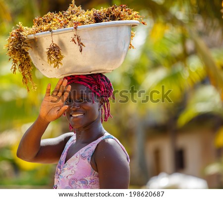 TAKORADI, GHANA - MARCH 22: Unidentified african woman carry sea weeds on her head on March 22, 2014 in Takoradi, Ghana. Carrying things on head is general skill of African girls and women.