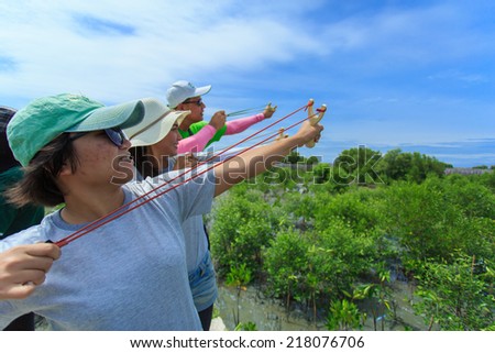 Samutsakorn Thailand, 16 September: Volunteers join together use catapult to shoot mangrove seeds to soil at far area in mangrove reforestation project on September 16, 2014 in Samutsakorn Thailand.