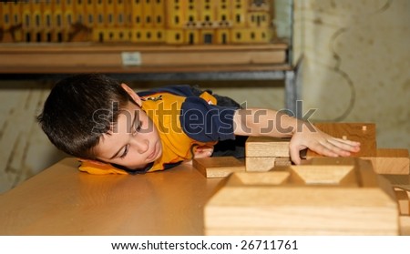Cute little boy plays with wooden bricks and builds a house