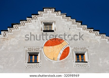 Red and orange sundial on wall of european house