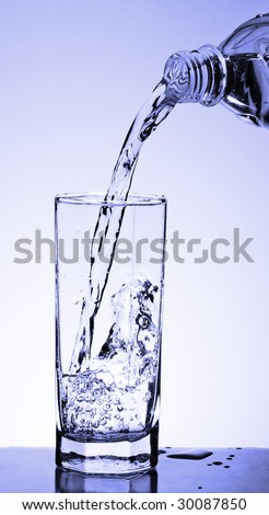 Water flowing from a bottle in a glass. Studio shooting.