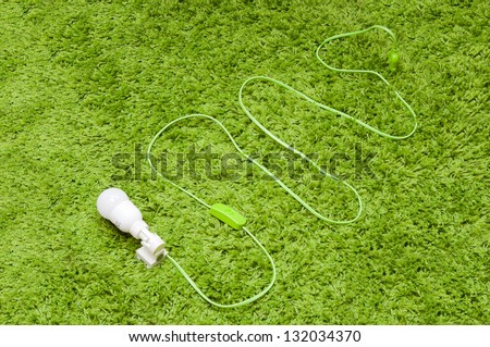 Energy saving lamp in the socket, with green wire, on the green carpet.