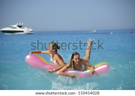 Mother with daughter getting fun at the inflatable mattress on the big wave