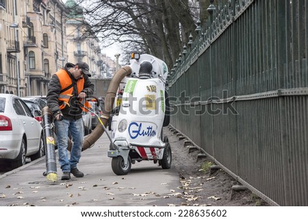 Migrant worker cleaning the Tavricheskaya st., from the leaves, by big vacuum cleaner. Russia, Saint-Petersburg, Tavricheskay st. 05/11/2014