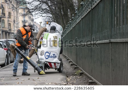 Migrant worker cleaning the Tavricheskaya st., from the leaves, by big vacuum cleaner. Russia, Saint-Petersburg, Tavricheskay st. 05/11/2014