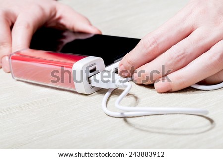 The woman charges the smartphone by external battery.