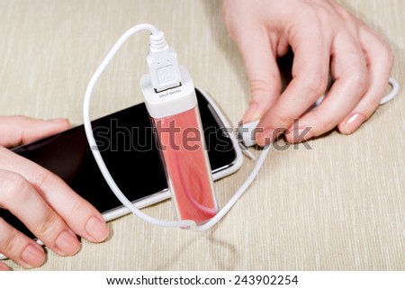 The woman charges the smartphone by external battery.