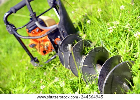 Motor earth auger on the grass