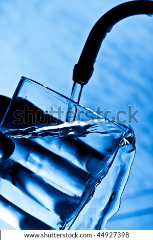 The woman pours water from the crane in a glass