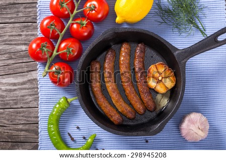 grilled sausages on a batch pan on an old wooden table, view from above