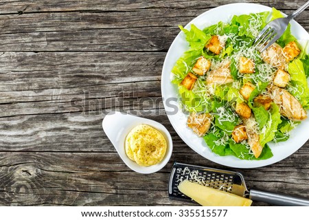 Delicious salad with croutons, grilled chicken breast, grated parmesan cheese and cos lettuce,  with sauce in the gravy boat, simply and healthy recipe, horizontal top view