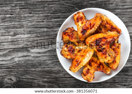 tasty grilled chicken wings on a white dish, top view