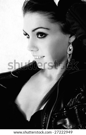 female model head shot in black and white looking away from the camera with one arm up on her head and her top open to slightly reveal the edge of her breast.