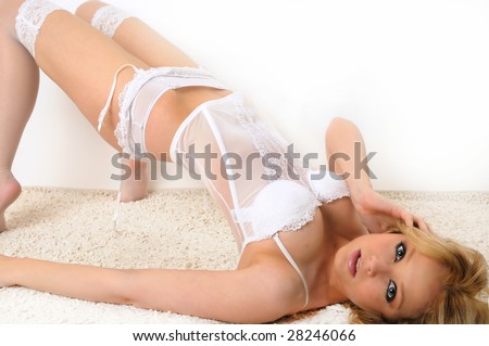 female model lying on her back pushing up and balancing on her shoulders and tip toes wearing a white corset, knickers, stockings and suspenders.