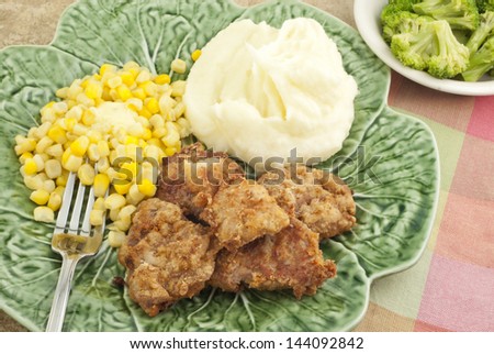 A delicious meal of pork tenderloin, corn, mashed potatoes, and broccoli, top view