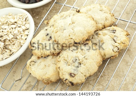 Fresh baked homemade oatmeal raisin cookies cooling on a wire rack with selective focus on ingredients