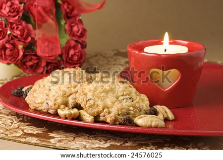 Oatmeal Raisin Cookies on a red plate with burning red heart candle and roses for Valentines Day