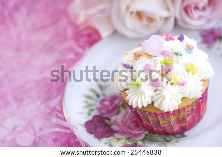 stock photo Pretty vanilla cupcake with sprinkles and pink candy heart