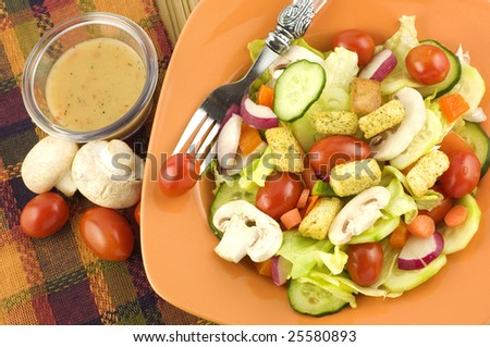 Colorful fresh garden salad with mushrooms in an orange bowl with fork  copy space