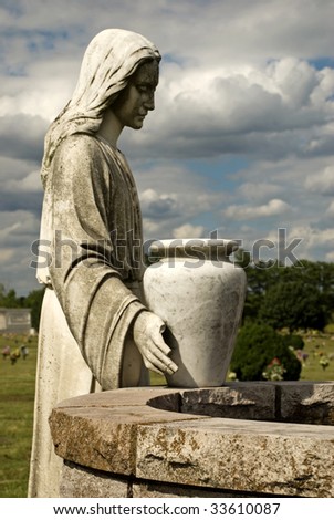 A cemetery statue of woman at the well, with water vessel, vertical with moody cloudy sky, copy space