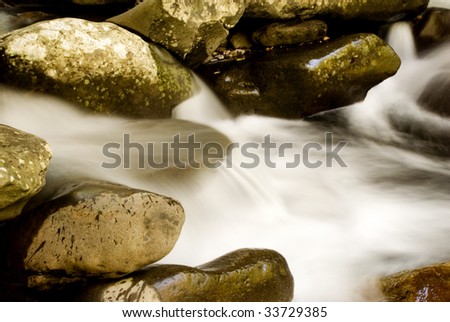 A beautiful silky smooth flowing waterfall, rushing over large rocks, horizontal with copy space, slow shutter speed