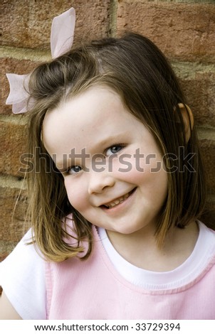 A cute little girl with big smile wearing pink clothing with pink hair bow, shallow depth of field, vertical with copy space