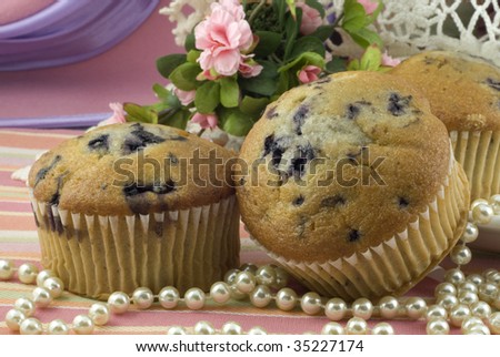 Delicious fresh baked blueberry muffins,  vintage still life with feminine setup, pearls, roses, lace, with pink decorations, horizontal, shallow depth of field