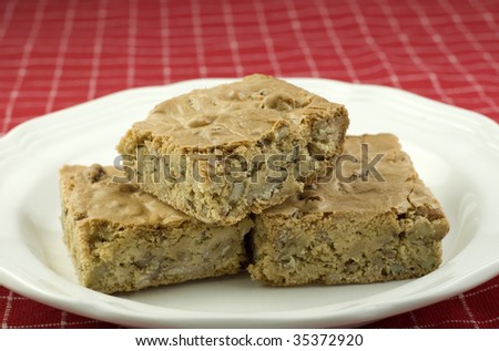 A plate of delicious pecan caramel bars, great for holidays or any time, red background with shallow depth of field, horizontal with copy space
