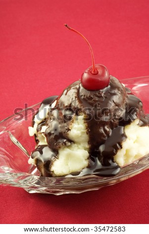 An delicious ice cream sundae with chocolate sauce and a cherry on top, on a red background, vertical with copy space