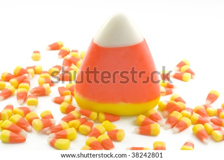 A Giant Candy Corn and small candy corn scattered around, isolated on white, copy space