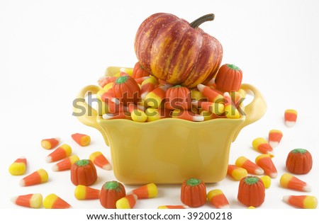 Halloween Candy Corn in a yellow candy dish with a little pumpkin on top, horizontal with copy space, isolated on white background