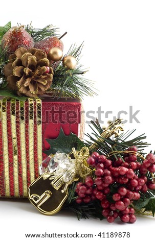 Beautiful red Christmas present with gold ribbon, tiny shiny gold guitar ornament with red berries and greenery, vertical with white copy space